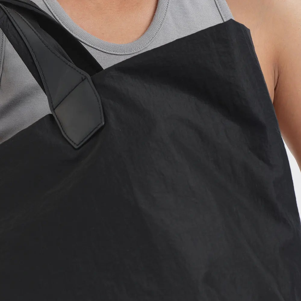 Close-up of the Porter Essence Black tote bag worn over a grey tank top, showcasing its sleek leather strap and ultra-light, crispy paper-touch nylon material.