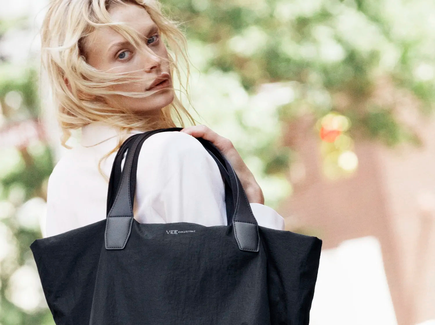 Woman holding Porter Essence Paper Black with a blurred outdoor background