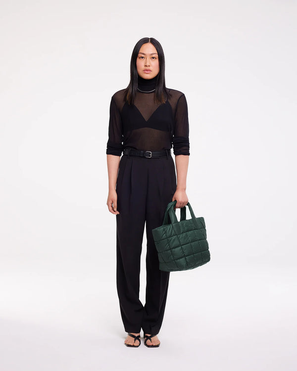 Full body picture of a woman holding the Porter Tote Bag Small in bottle green, arm extended slightly forward in front of her body.