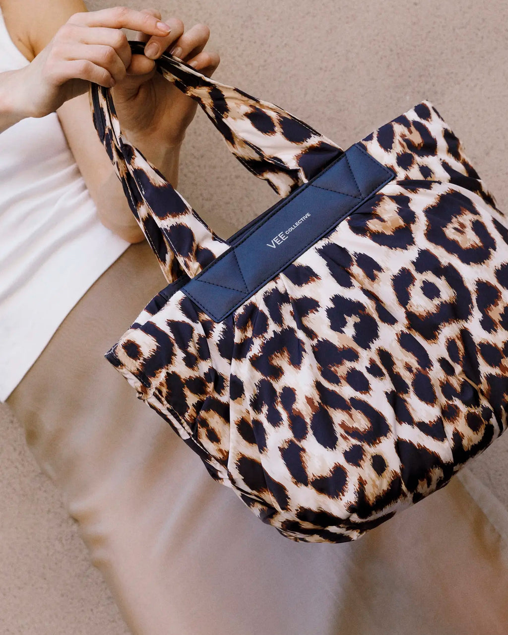 Leopard print handbag with a visible VEE COLLECTIVE logo held by a person.