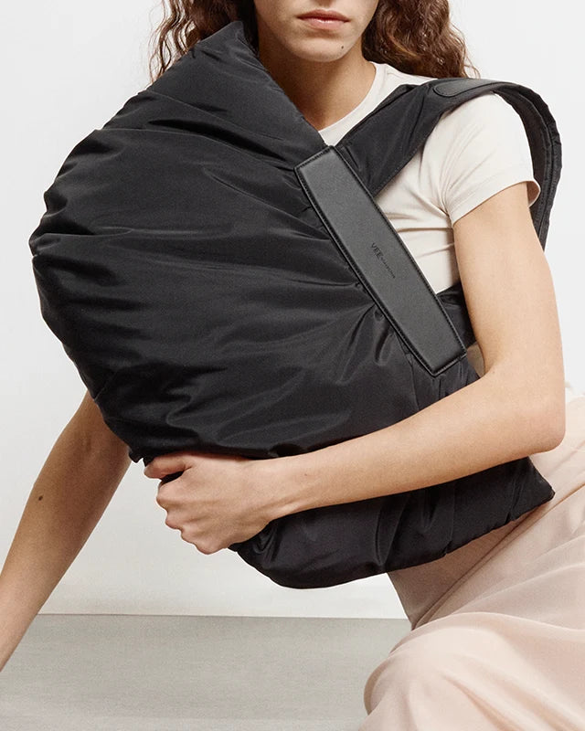 Woman in a beige outfit holding the Caba Medium Tote Bag in Black by Vee Collective in front of her body.