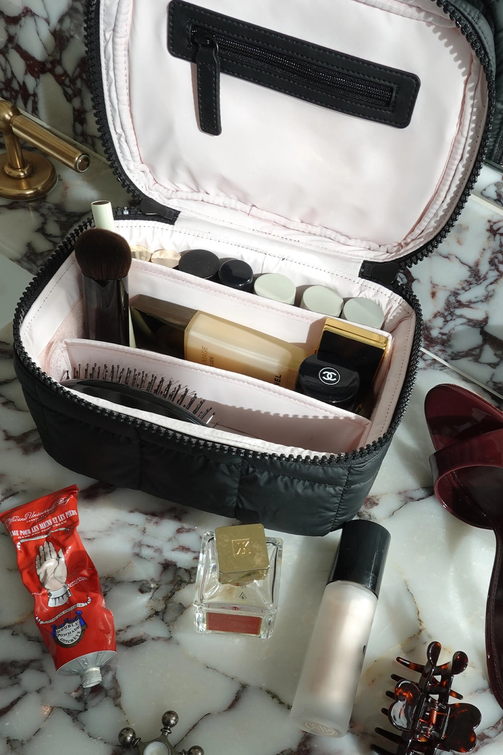 Open Vanity Case bag with cosmetic items on a marble surface