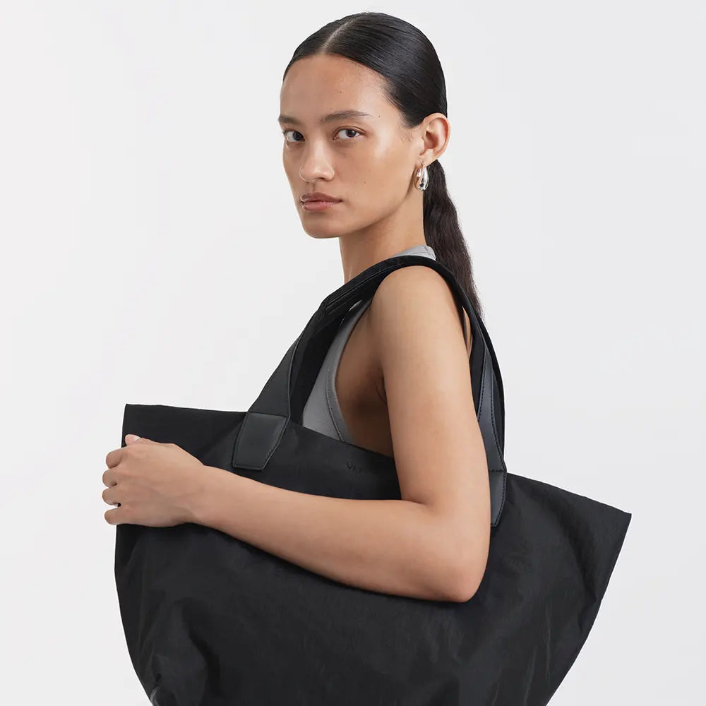 Woman holding Porter Essence Black bag against a plain background
