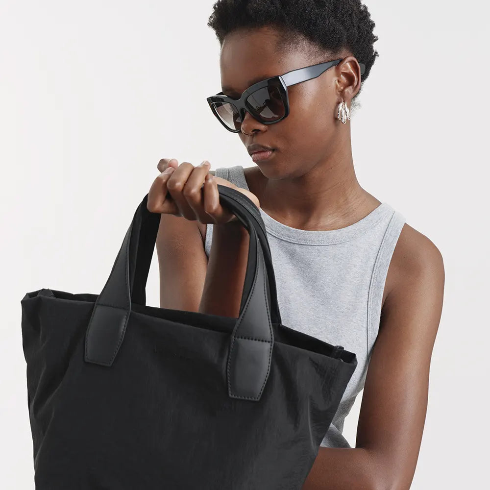 Woman holding Porter Essence Black bag against a plain background