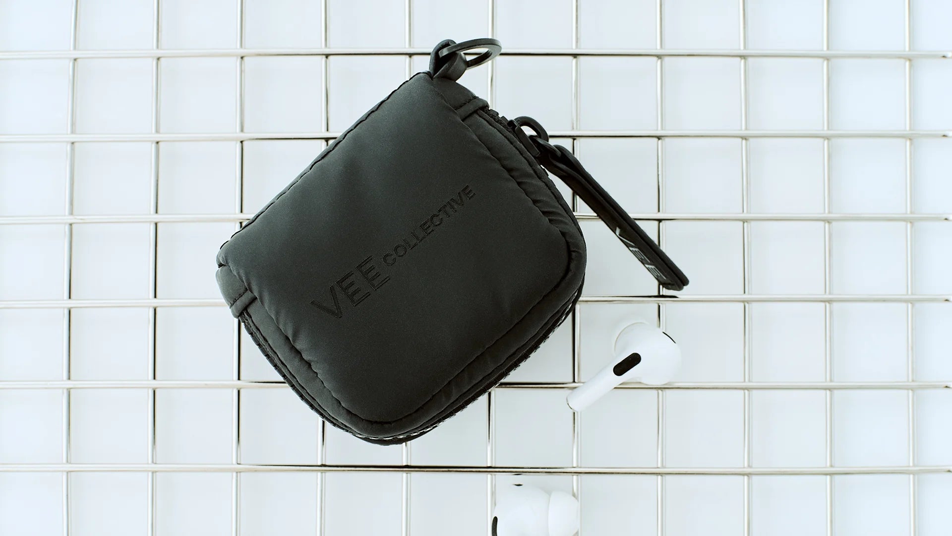 Porter Pods Case in matt black lying in a basket with a pair of AirPods.