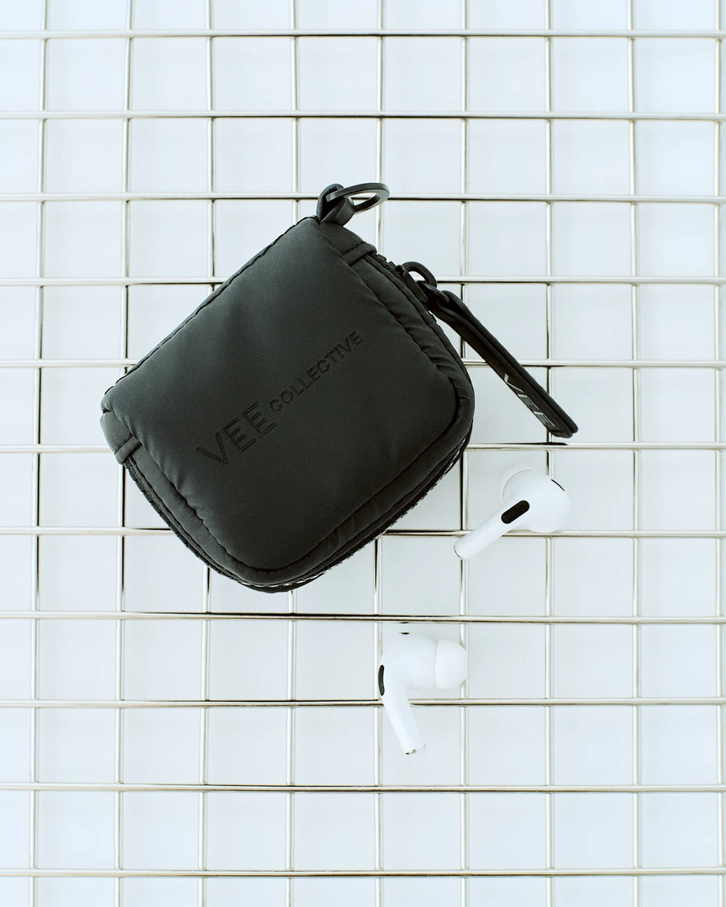 Porter Pods Case in matt black lying in a basket with AirPods.