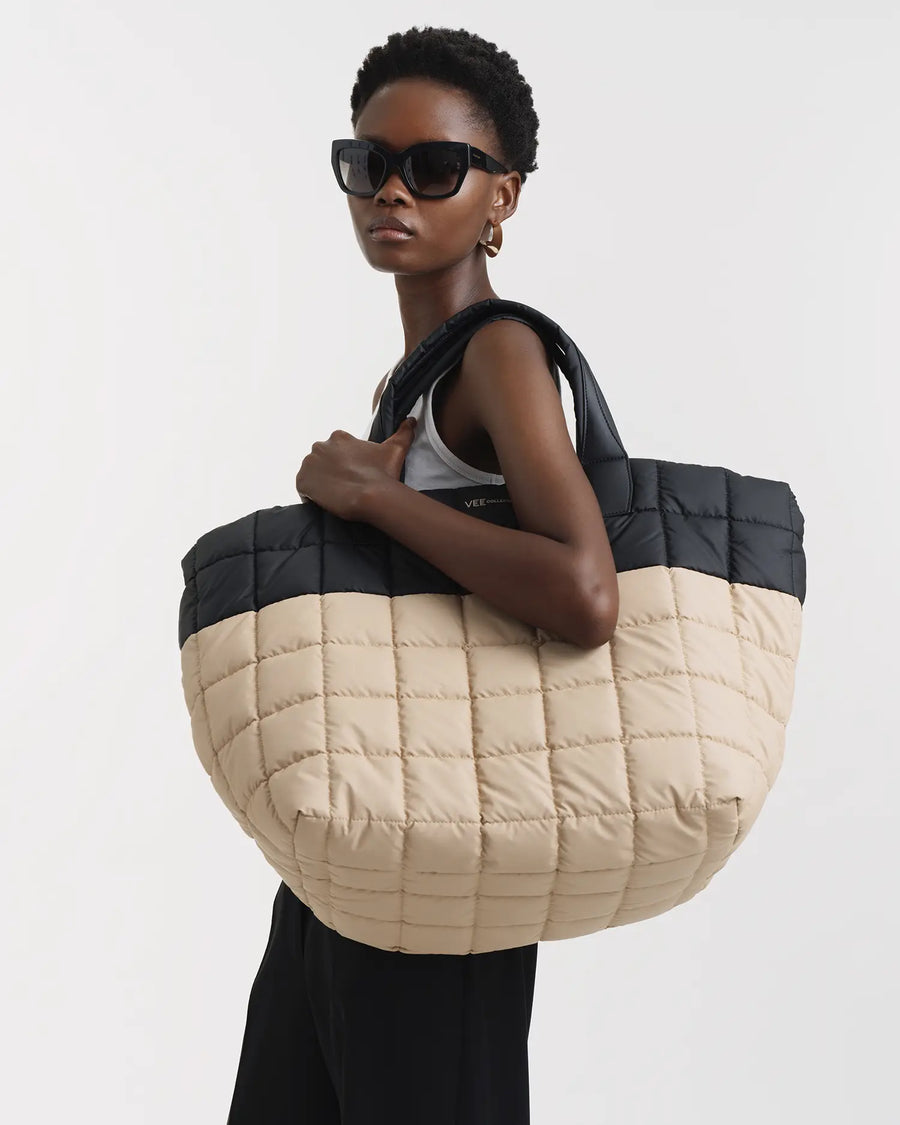 Woman holding a large quilted tote bag with a black and beige design on a white background