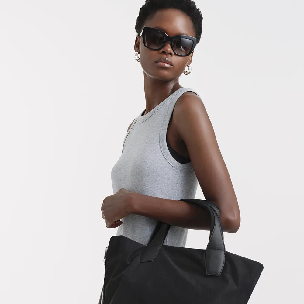 Woman holding Porter Essence Black handbag against a plain background
