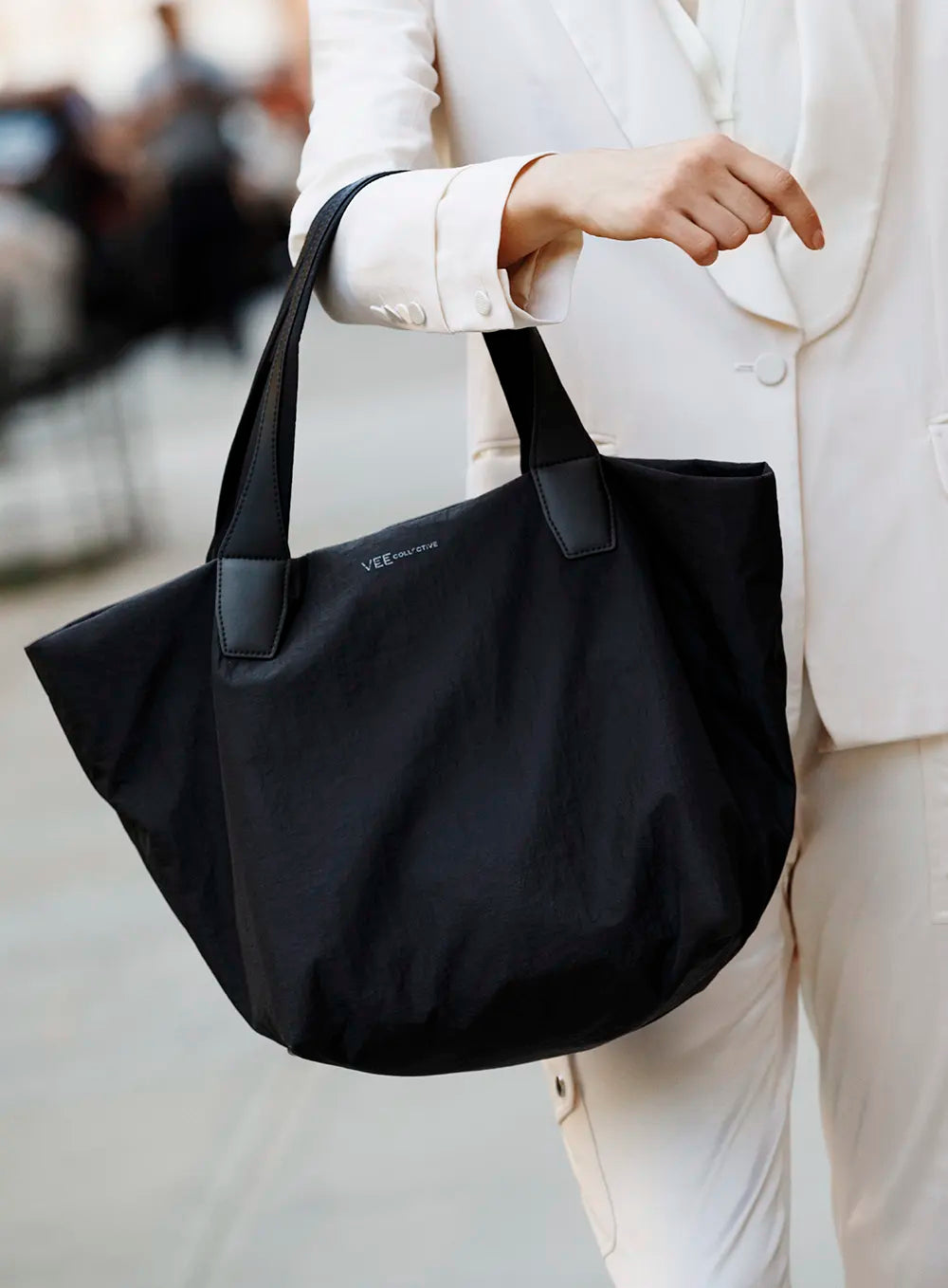 Person holding a Porter Essence Black Paper handbag with a blurred background