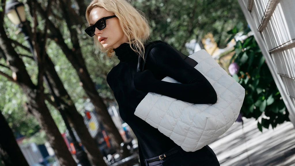 Woman holding a white quilted handbag in an urban setting