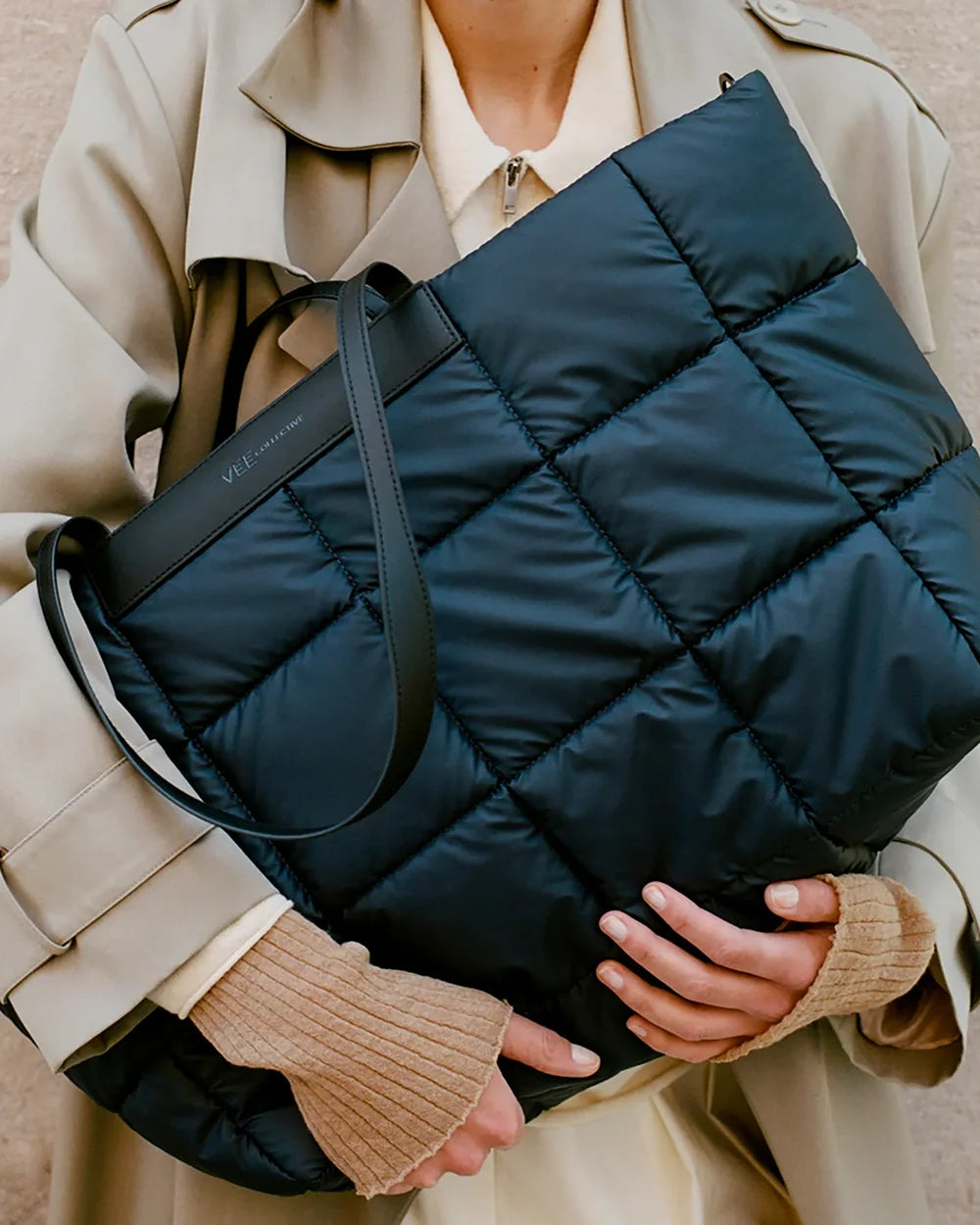 Person holding a dark blue quilted bag 