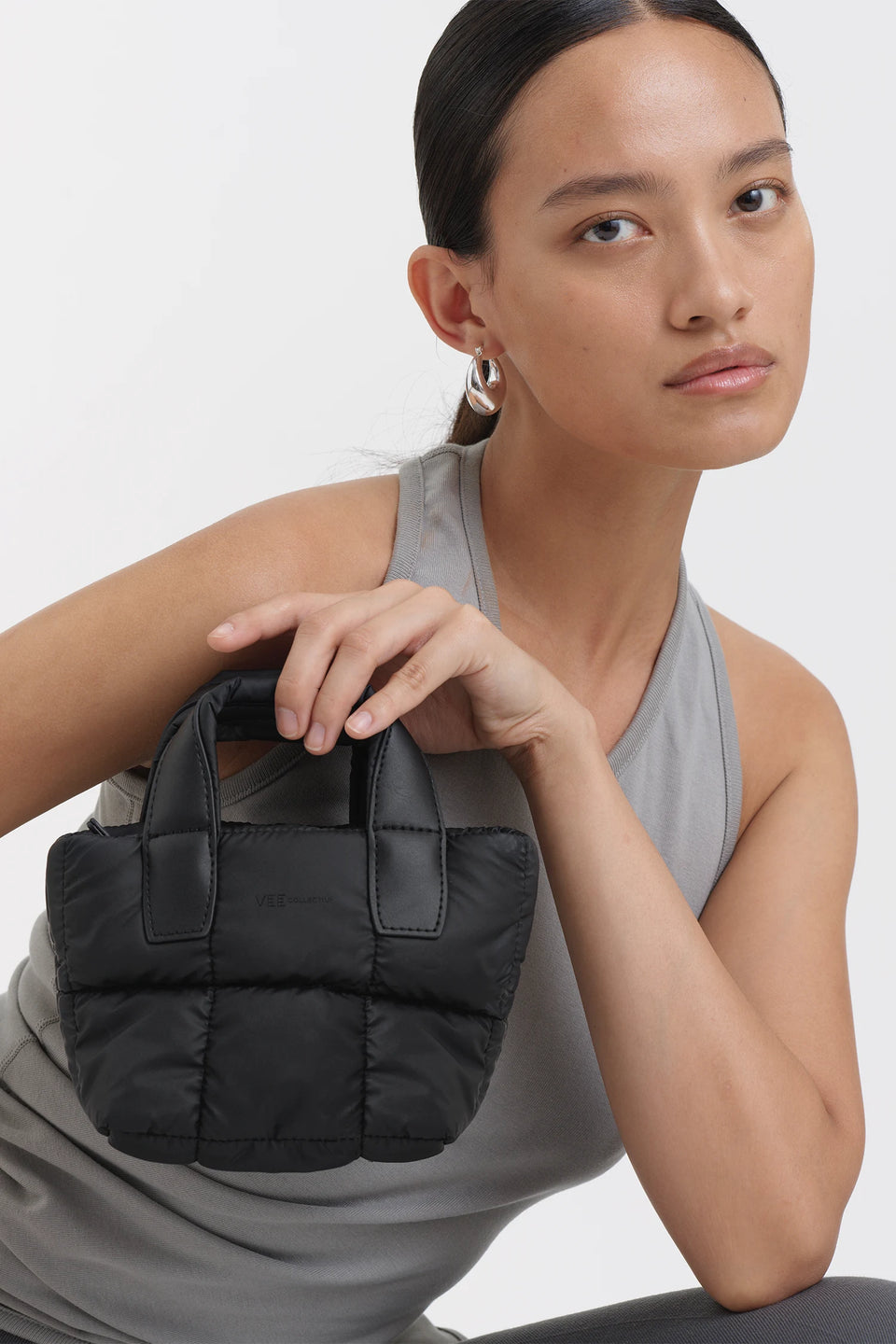 Stylish woman holding a black micro tote bag, showcasing versatility as a crossbody or tote bag option.