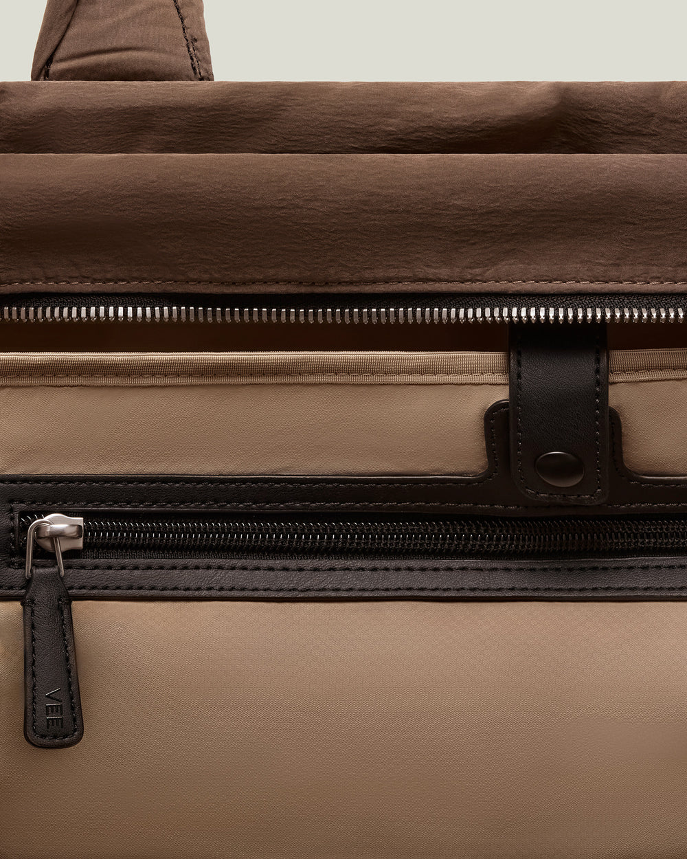 A close-up product photo of an Essence City Tote bag in mink with black leather trim, featuring a front zip pocket and a top handle, displayed against a clean white background.