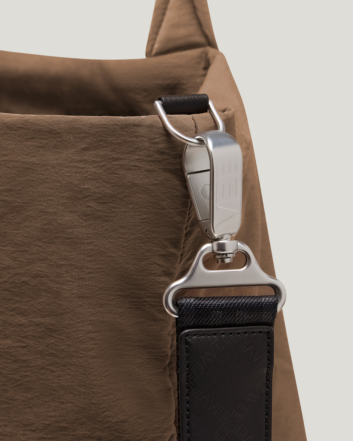 A close-up product photo of a mink Essence bag featuring a black strap with silver metal hardware, displayed against a clean white background.
