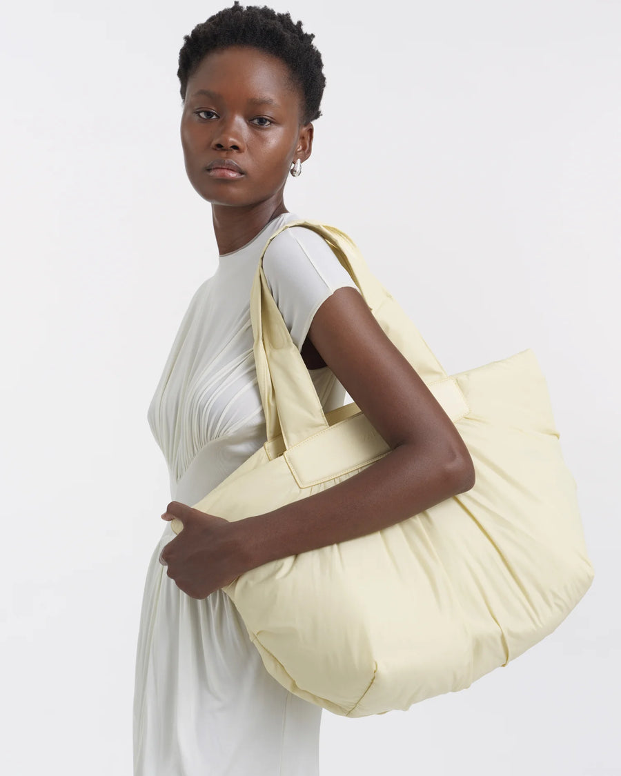 Side view of a woman carrying the Galvan x Vee Collective Caba Medium Tote Bag in buttermilk over her shoulder.