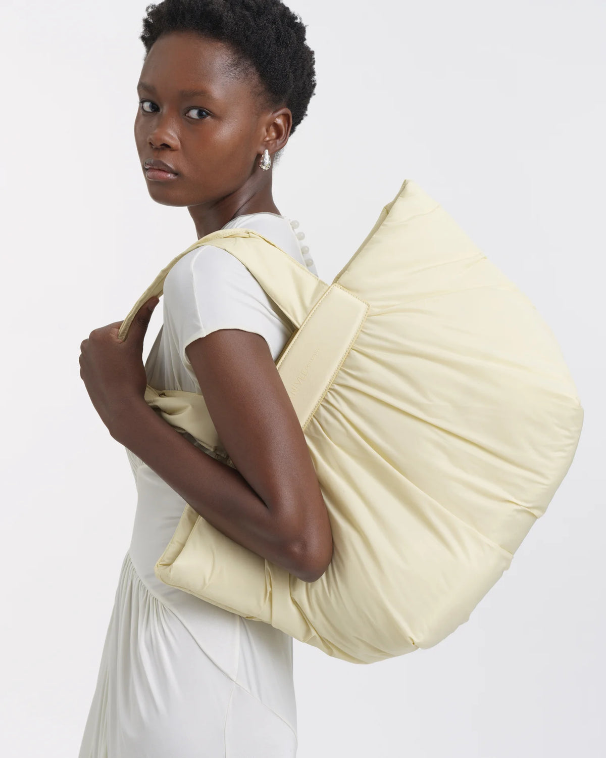 Woman carrying the Galvan x Vee Collective Caba Medium Tote Bag in buttermilk over her shoulder.