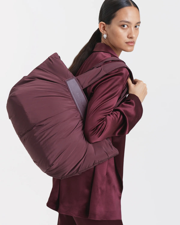 Woman wearing a mahogany outfit carrying the Galvan x Vee Collective Caba Medium Tote Bag in mahogany over her shoulder.