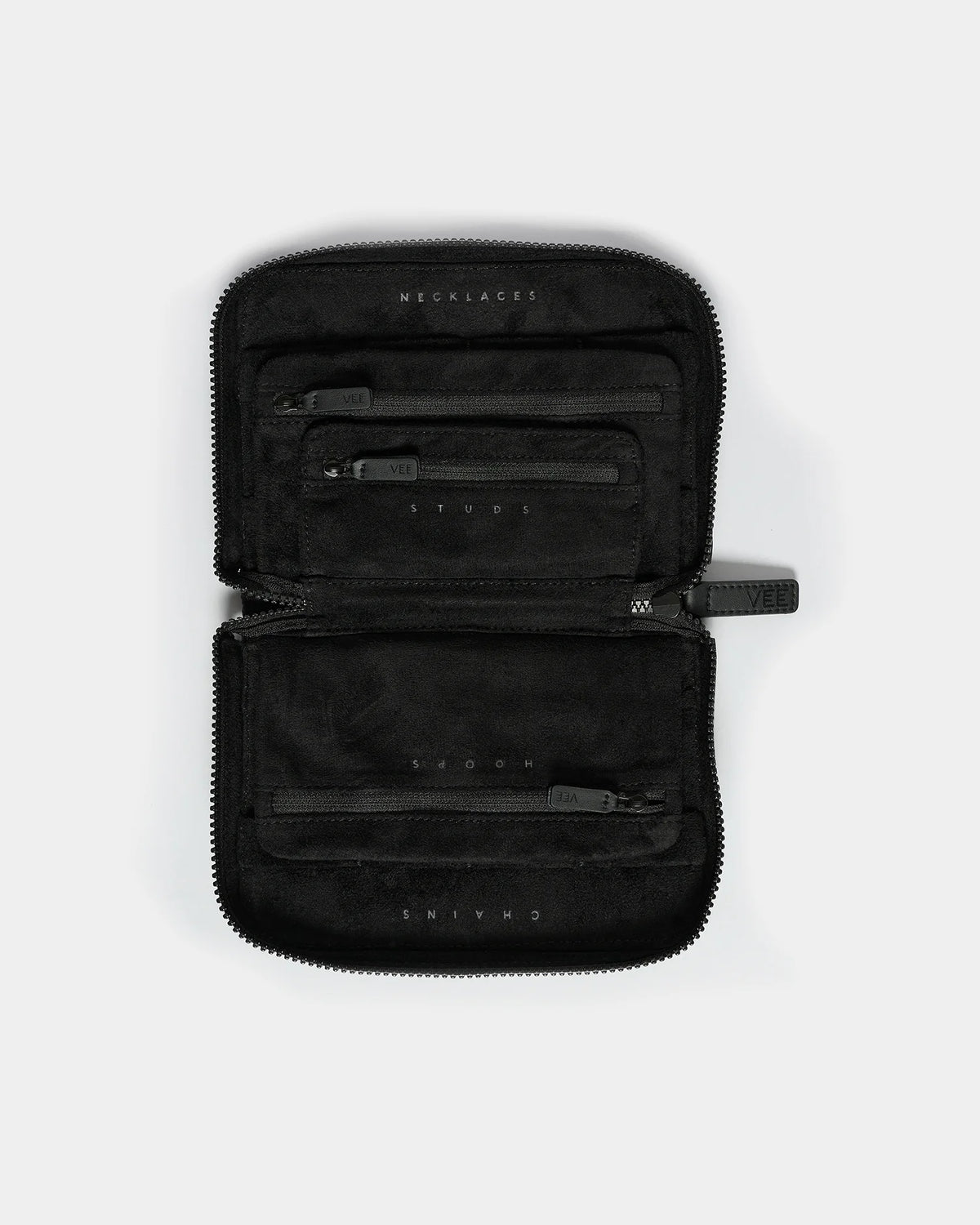 The image features an open black jewelry case with a quilted exterior and a soft black interior. It showcases three zippered compartments labeled for organizing necklaces, studs, and chains, emphasizing its functional design.