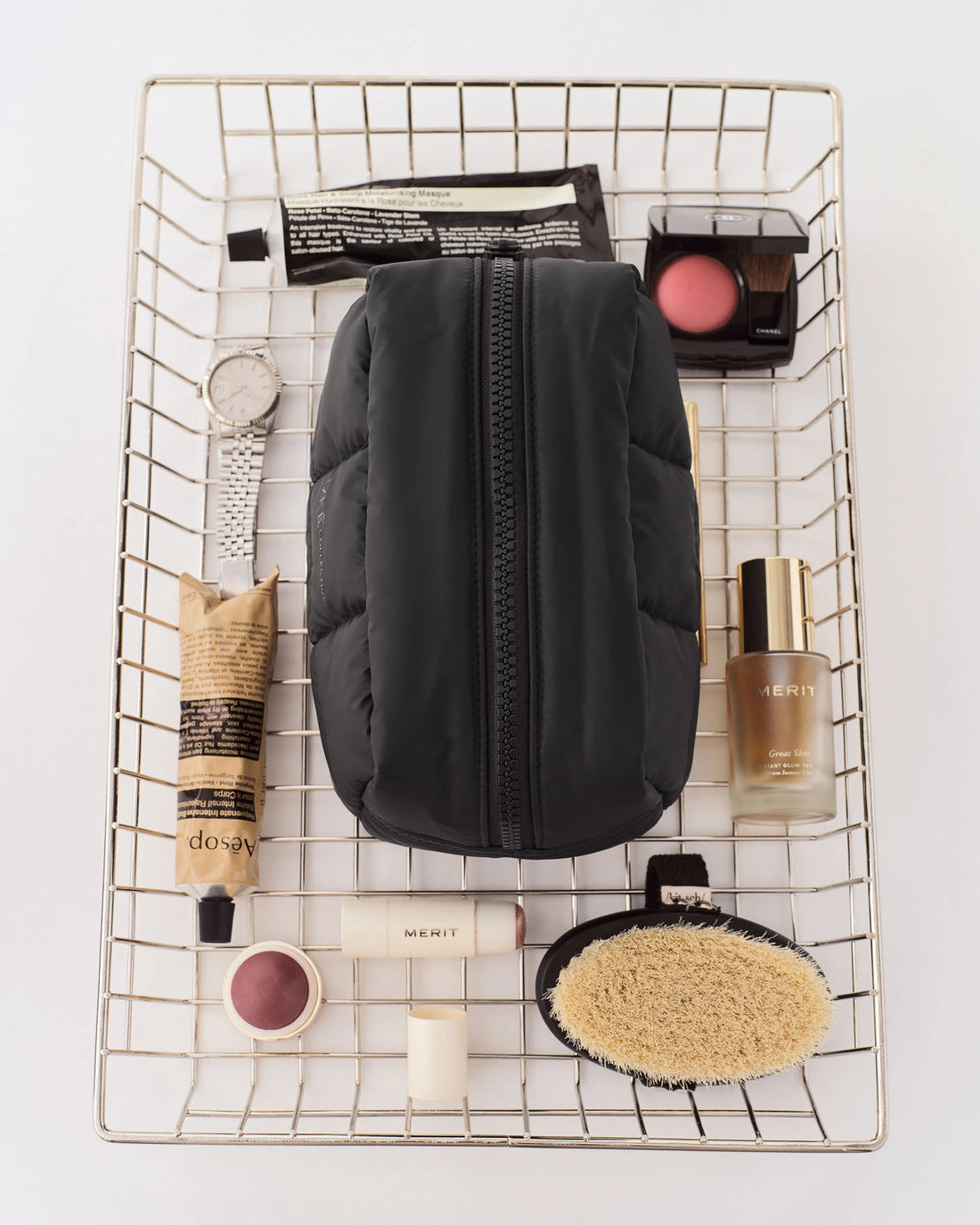 Porter Cosmetics Pouch Medium Matt Black in a metal wire basket with beauty products.