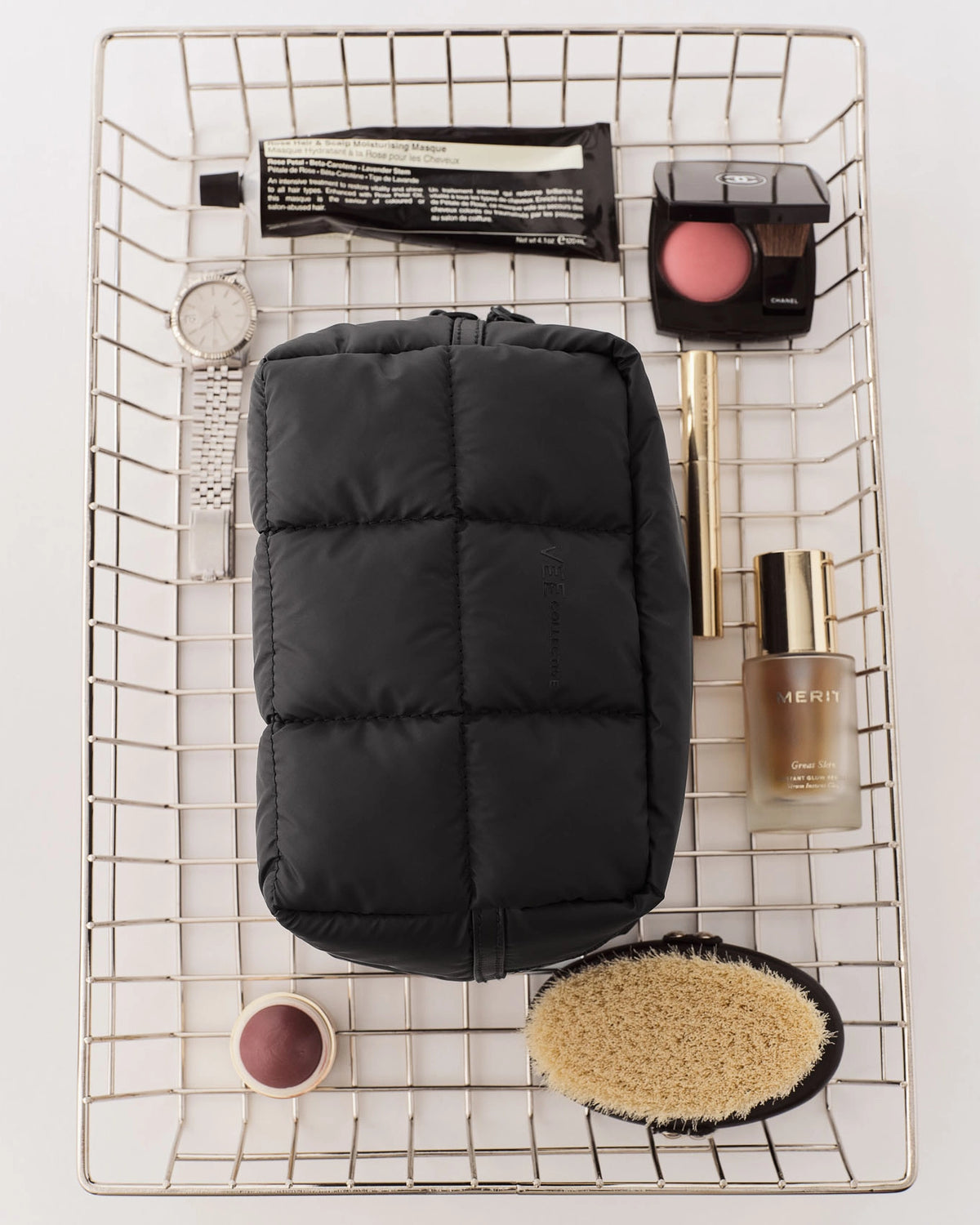 Porter Cosmetics Pouch Small Matt Black in a metal wire basket with makeup items.