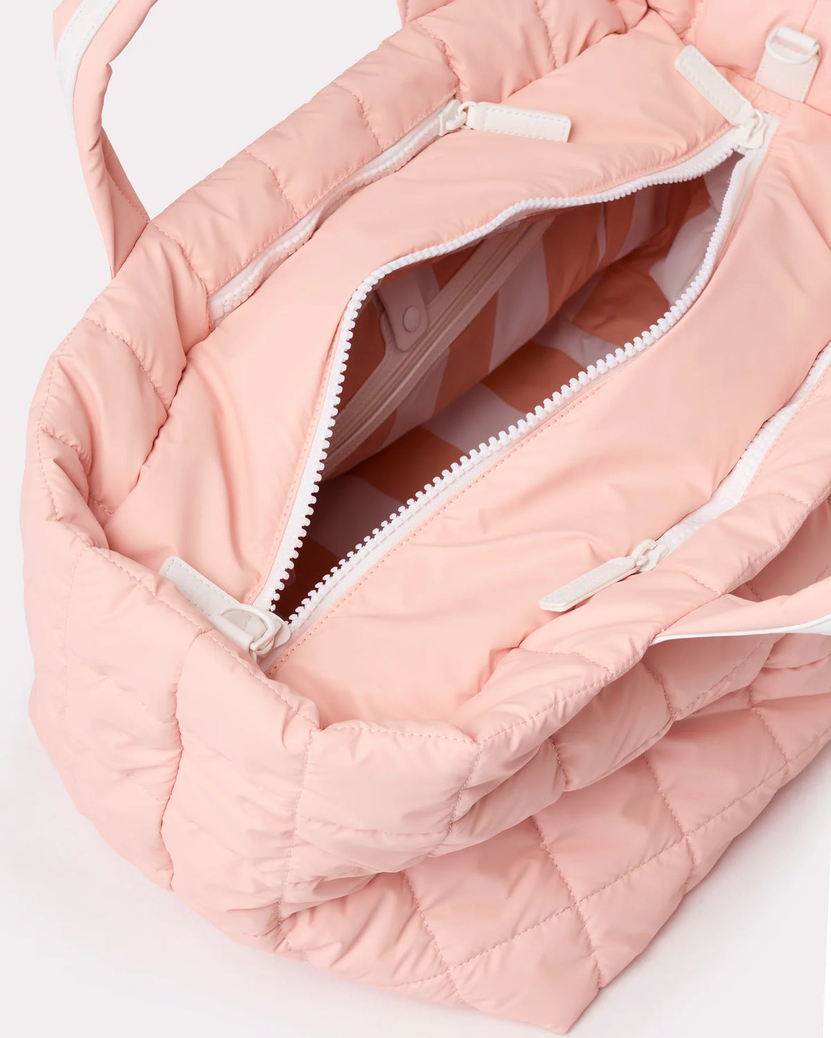 Open pink quilted Weekender showing white zipper and striped interior lining.