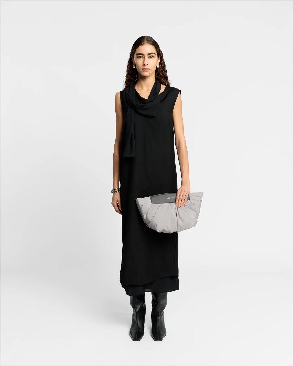 On-body picture of a woman holding the Caba Clutch bag in Dove by Vee Collective, wearing a minimalistic outfit against a clean studio background.