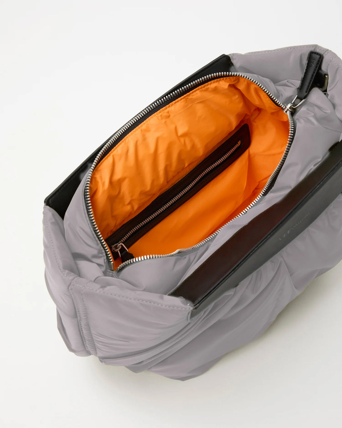 Open Vee Collective Caba Clutch in Dove, showing the quilted exterior, top zipper, and orange interior of the Clutch bag.