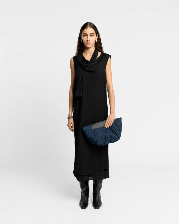 On-body picture of a woman holding the Caba Clutch bag in Marine by Vee Collective, wearing a minimalistic outfit against a clean studio background.