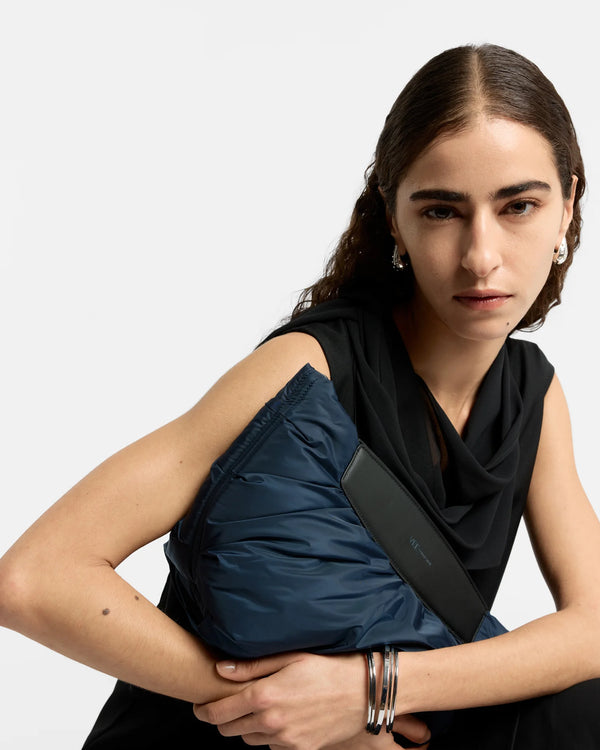 Upper-body close-up of a woman carrying the Caba Clutch bag in Marine by Vee Collective, wearing a minimalistic outfit against a clean studio background.