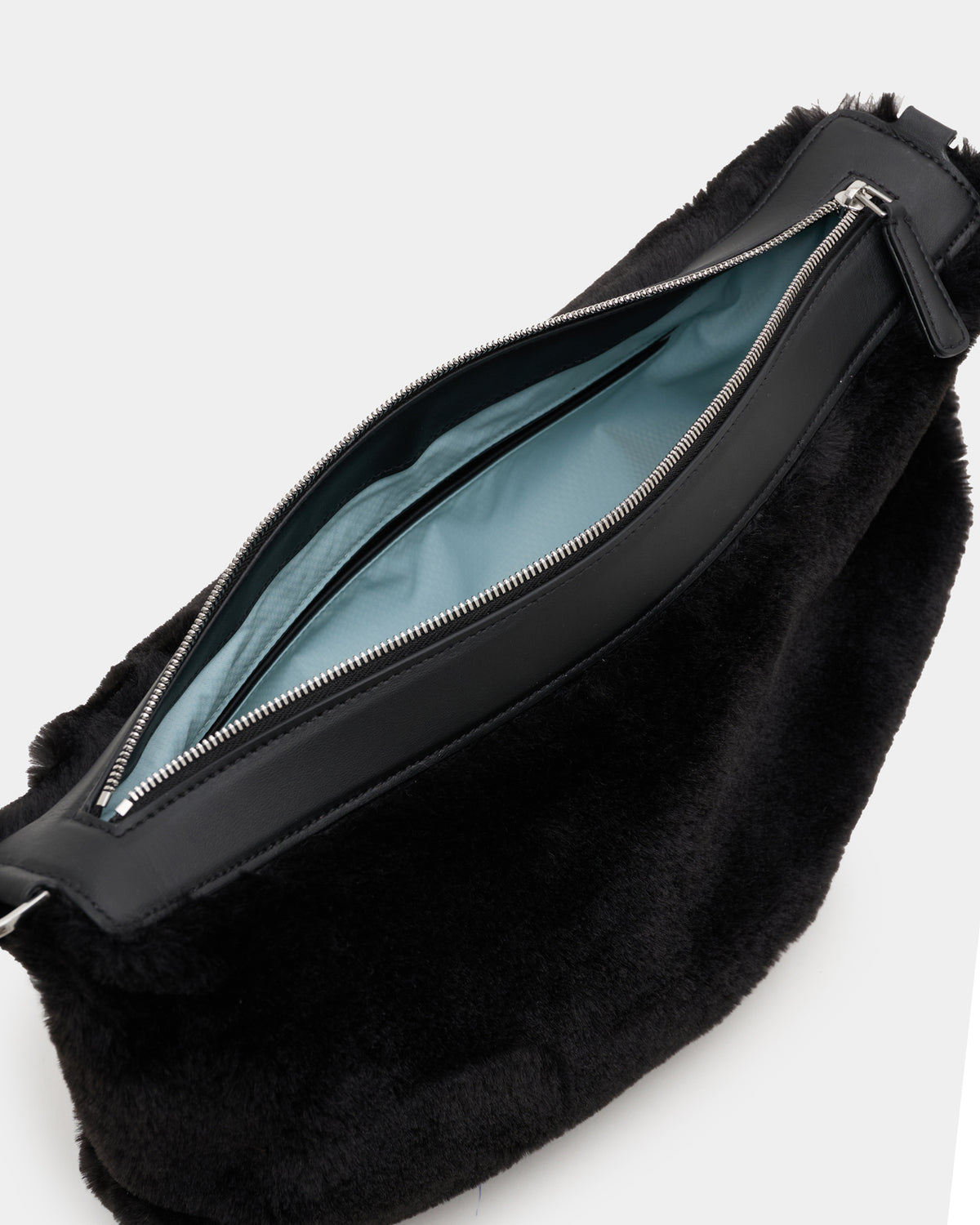 A close-up of a Caba fur Banana bag with a black leather zipper trim and a light blue interior lining, shown on a white background.