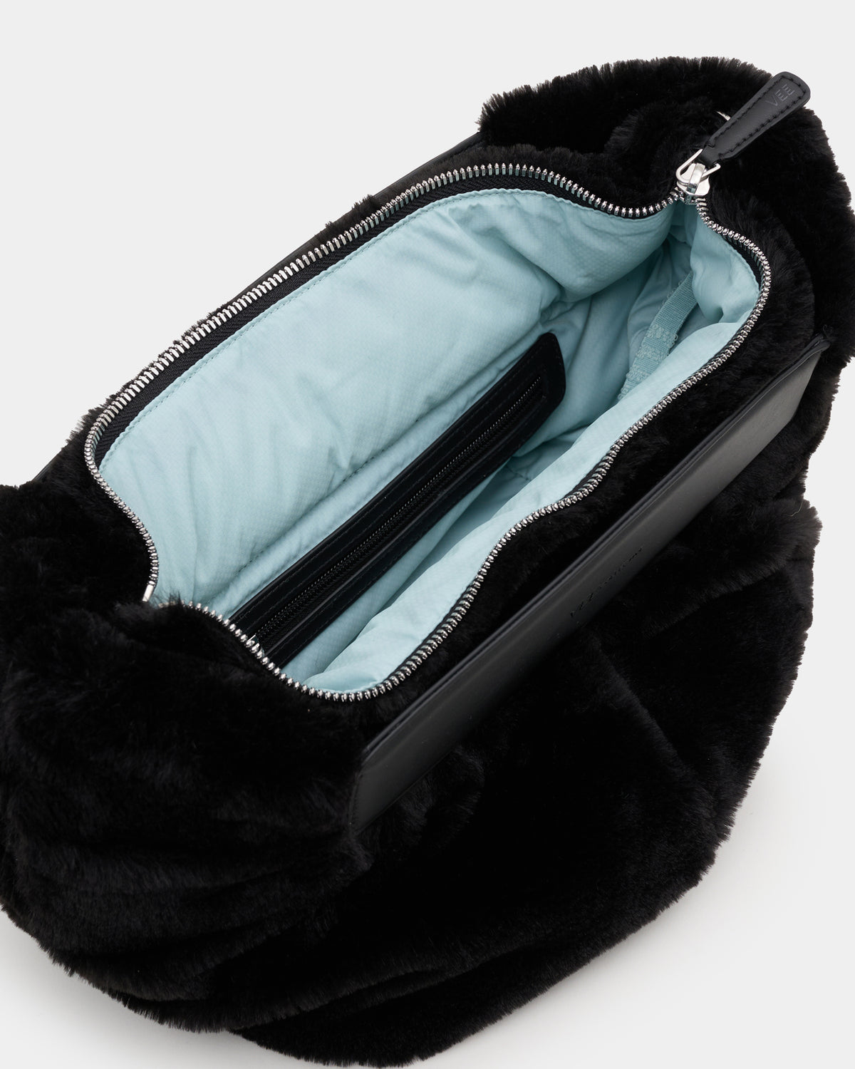 A close-up of a Caba fur Banana bag with a black leather zipper trim and a light blue interior lining, shown on a white background.