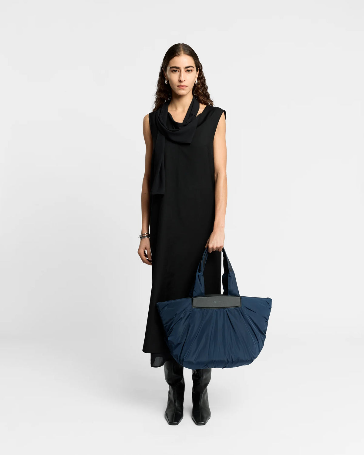 On-body picture of a woman holding the Caba Tote bag Medium in Marine by Vee Collective, wearing a minimalistic outfit against a clean studio background.