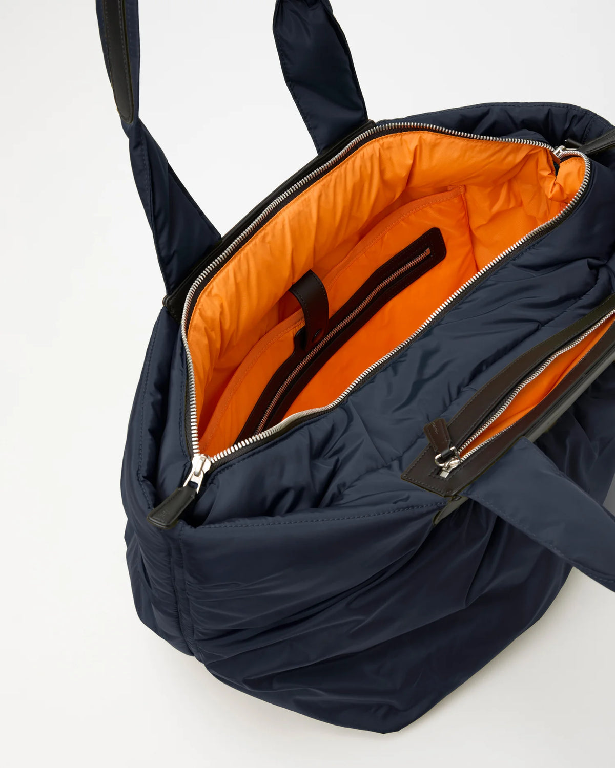 Open Vee Collective Caba Tote Bag Medium in Marine, showing the quilted exterior, top zipper, and orange interior of the tote bag.