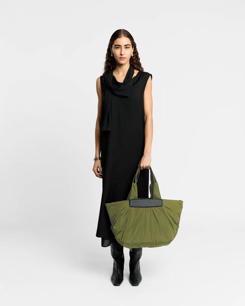 Woman wearing a clean outfit holding the Vee Collective Caba Tote Bag Medium in Olive, shown against a clean background.