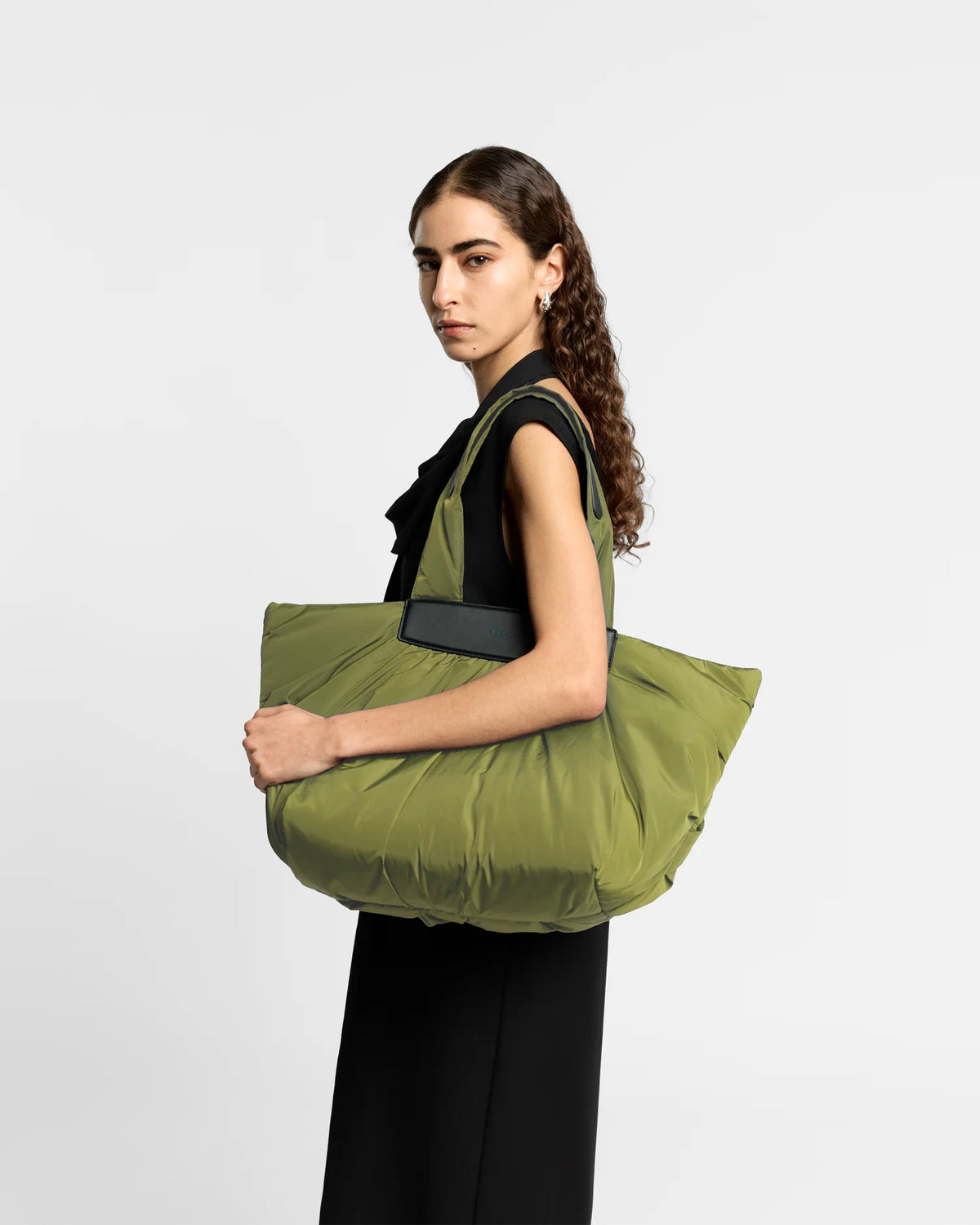 Woman wearing a clean outfit holding the Vee Collective Caba Tote Bag Medium in Olive, shown against a clean background.