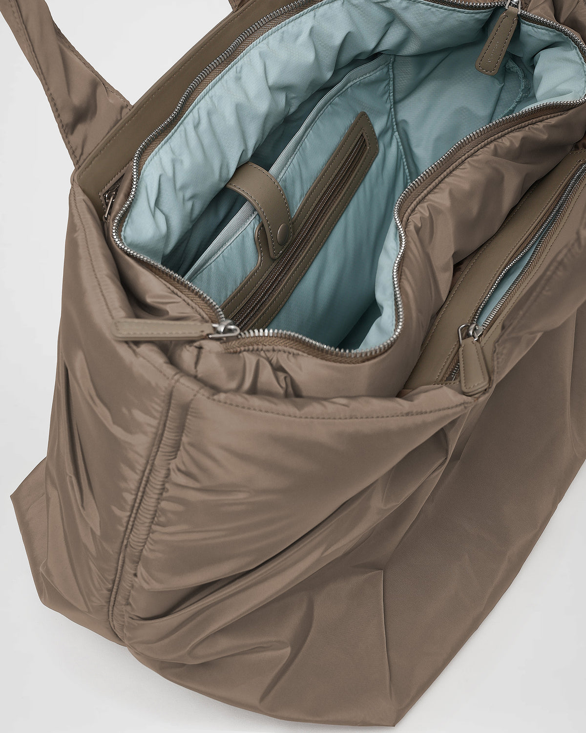A close-up photo of the interior of an Caba Tote, featuring black leather zipper pulls and a black zippered pocket with silver-tone metal zippers.
