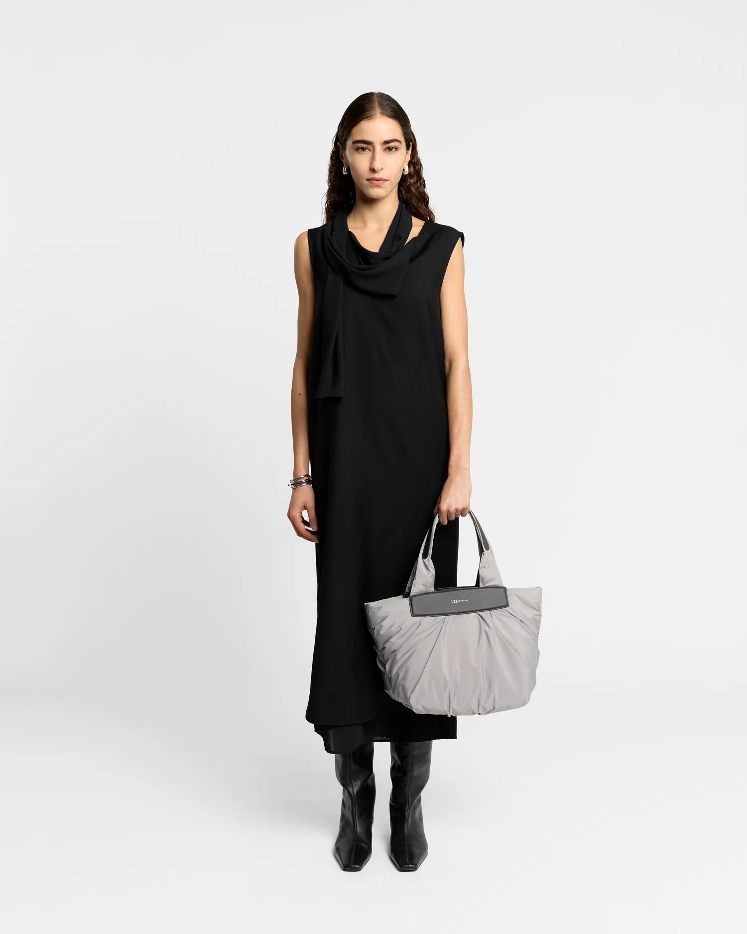 On-body picture of a woman holding the Small Caba Tote Bag in Dove by Vee Collective, wearing a minimalistic outfit against a clean studio background.