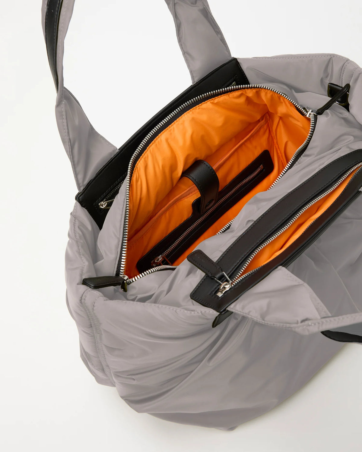 Open Vee Collective Caba Tote Bag Small in Dove, showing the quilted exterior, top zipper, and orange interior of the tote bag.