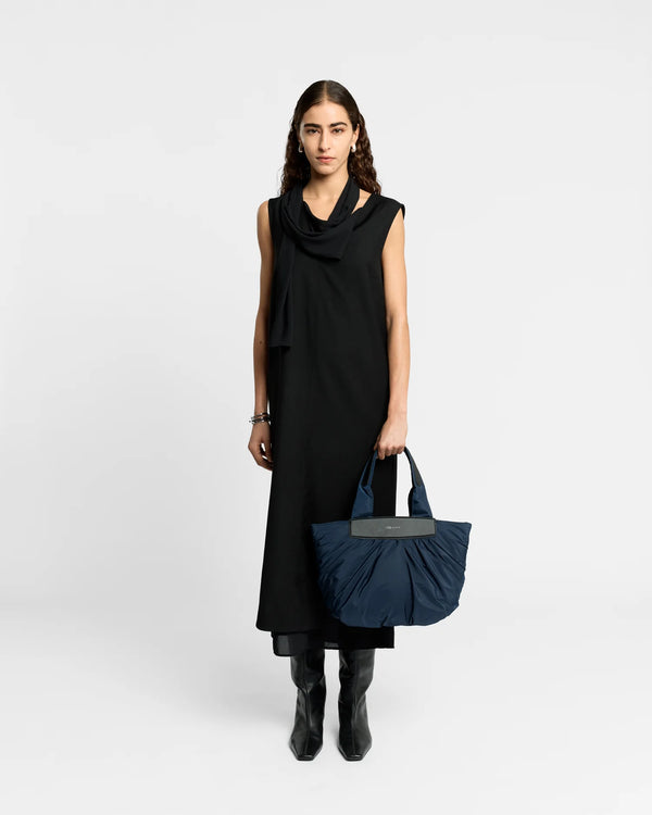 On-body picture of a woman holding the Small Caba Tote Bag in Marine by Vee Collective, wearing a minimalistic outfit against a clean studio background.