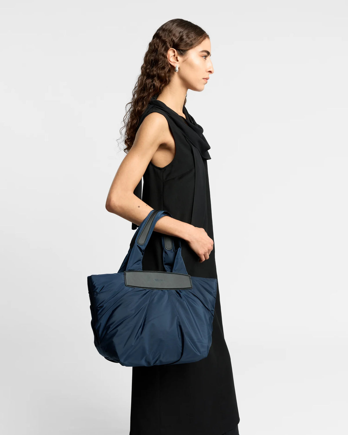 On-body picture of a woman carrying the Small Caba Tote Bag in Marine by Vee Collective, wearing a minimalistic outfit against a clean studio background.