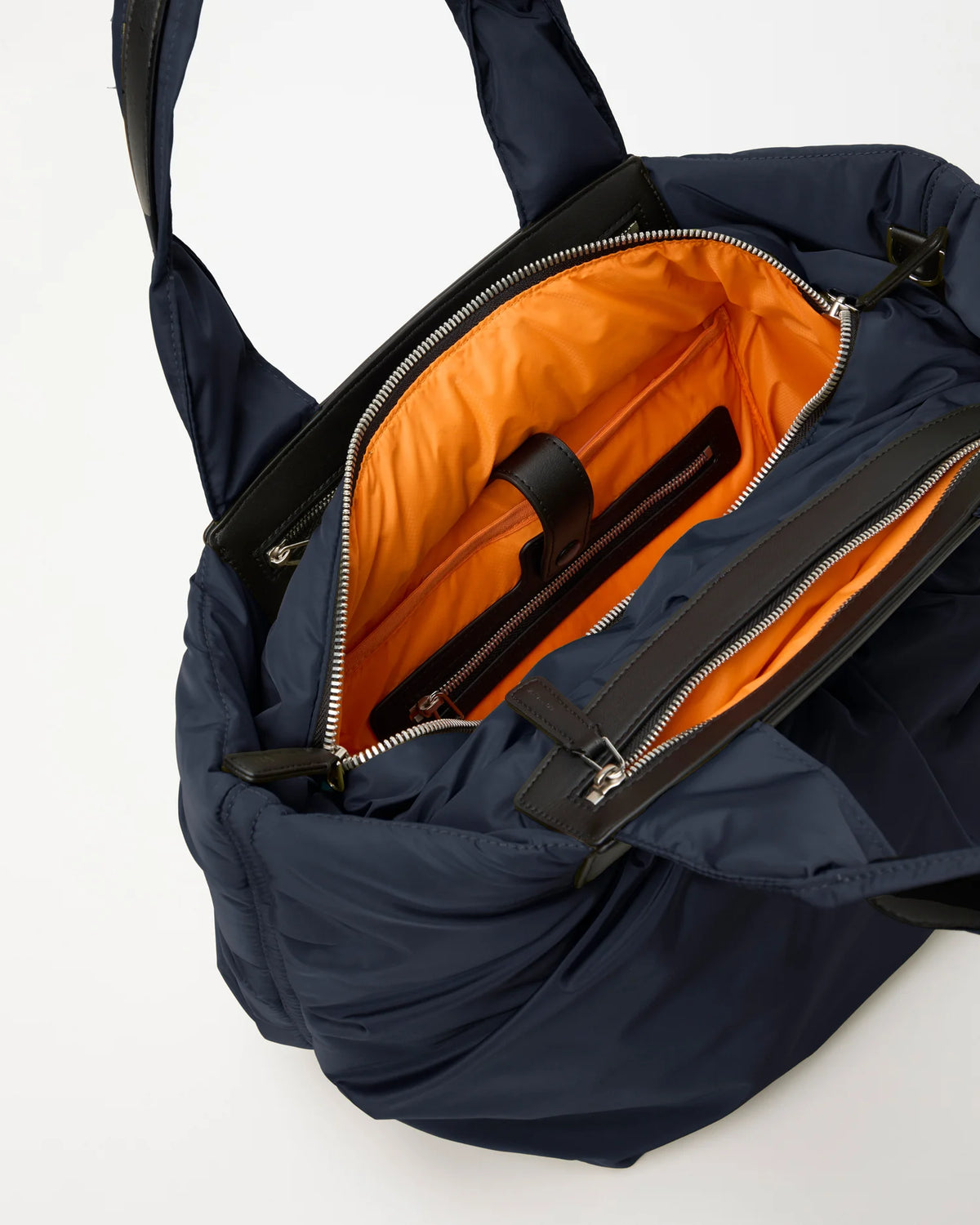 Open Vee Collective Caba Tote Bag Small in Marine, showing the quilted exterior, top zipper, and orange interior of the tote bag.