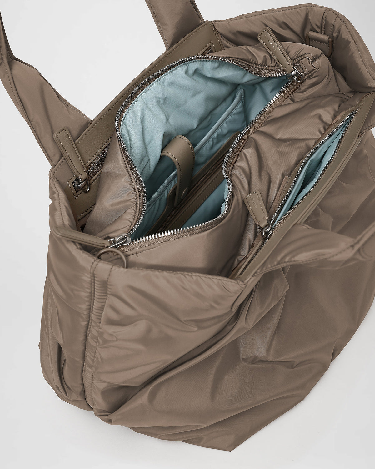 A close-up photo of the interior of an Caba Tote, featuring black leather zipper pulls and a black zippered pocket with silver-tone metal zippers.
