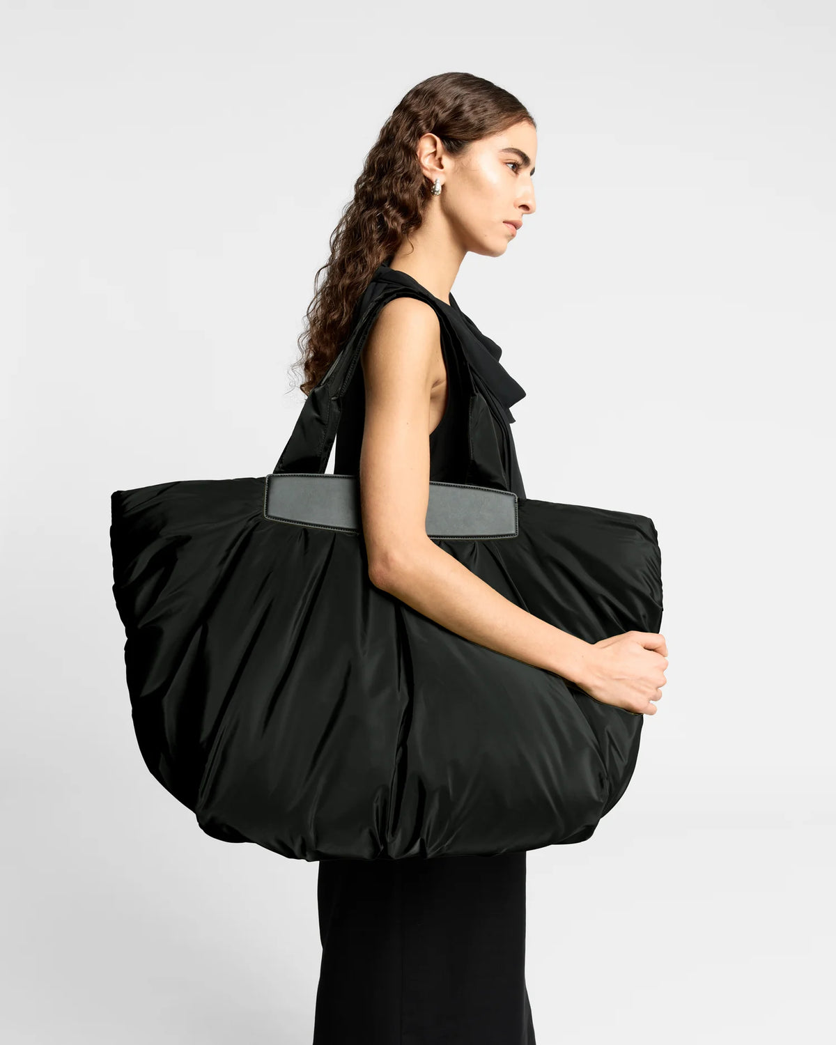 Woman wearing a clean outfit holding the Vee Collective Caba Weekender Tote Bag in Black, shown against a clean background.