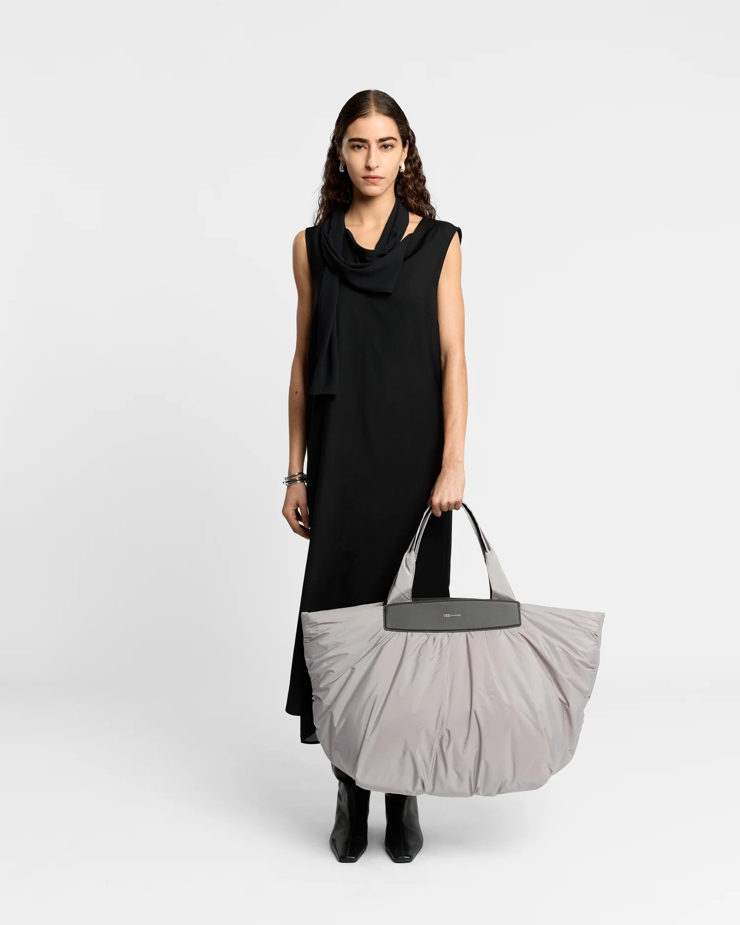 On-body picture of a woman holding the Caba Weekender Tote Bag in Dove by Vee Collective, wearing a minimalistic outfit against a clean studio background.