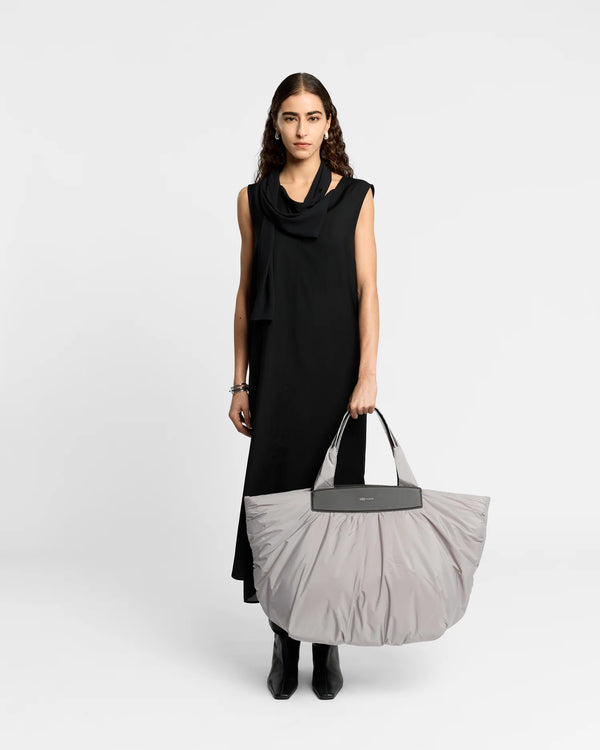 On-body picture of a woman holding the Caba Weekender Tote Bag in Dove by Vee Collective, wearing a minimalistic outfit against a clean studio background.