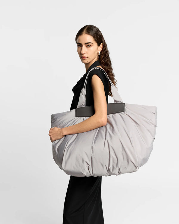 On-body picture of a woman carrying the Caba Weekender Tote Bag in Dove by Vee Collective, wearing a minimalistic outfit against a clean studio background.