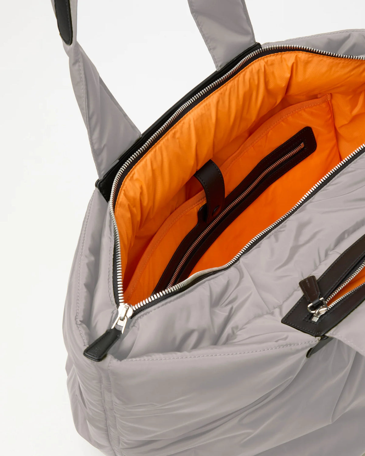 Open Vee Collective Caba Weekender Tote Bag in Dove, showing the quilted exterior, top zipper, and orange interior of the tote bag.