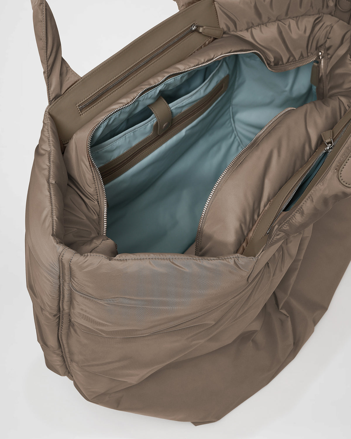 A close-up photo of the interior of an Caba Tote, featuring black leather zipper pulls and a black zippered pocket with silver-tone metal zippers.