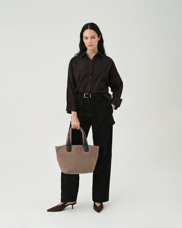 Woman in a beige trench coat carrying the Porter Essence Small Tote Bag in Mink Trench by Vee Collective against a plain studio background.