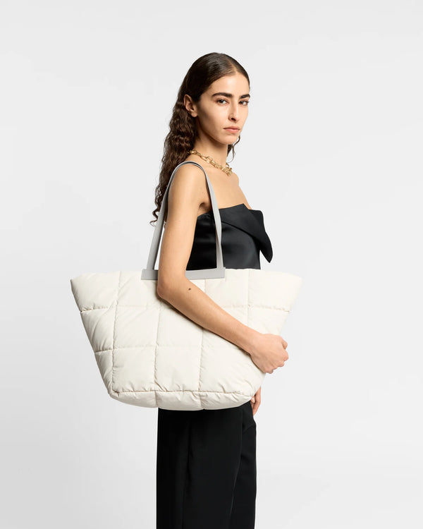 On-body picture of a woman carrying the Porter Basque Tote Bag in Barely Beige by Vee Collective, wearing a minimalistic outfit against a clean studio background.